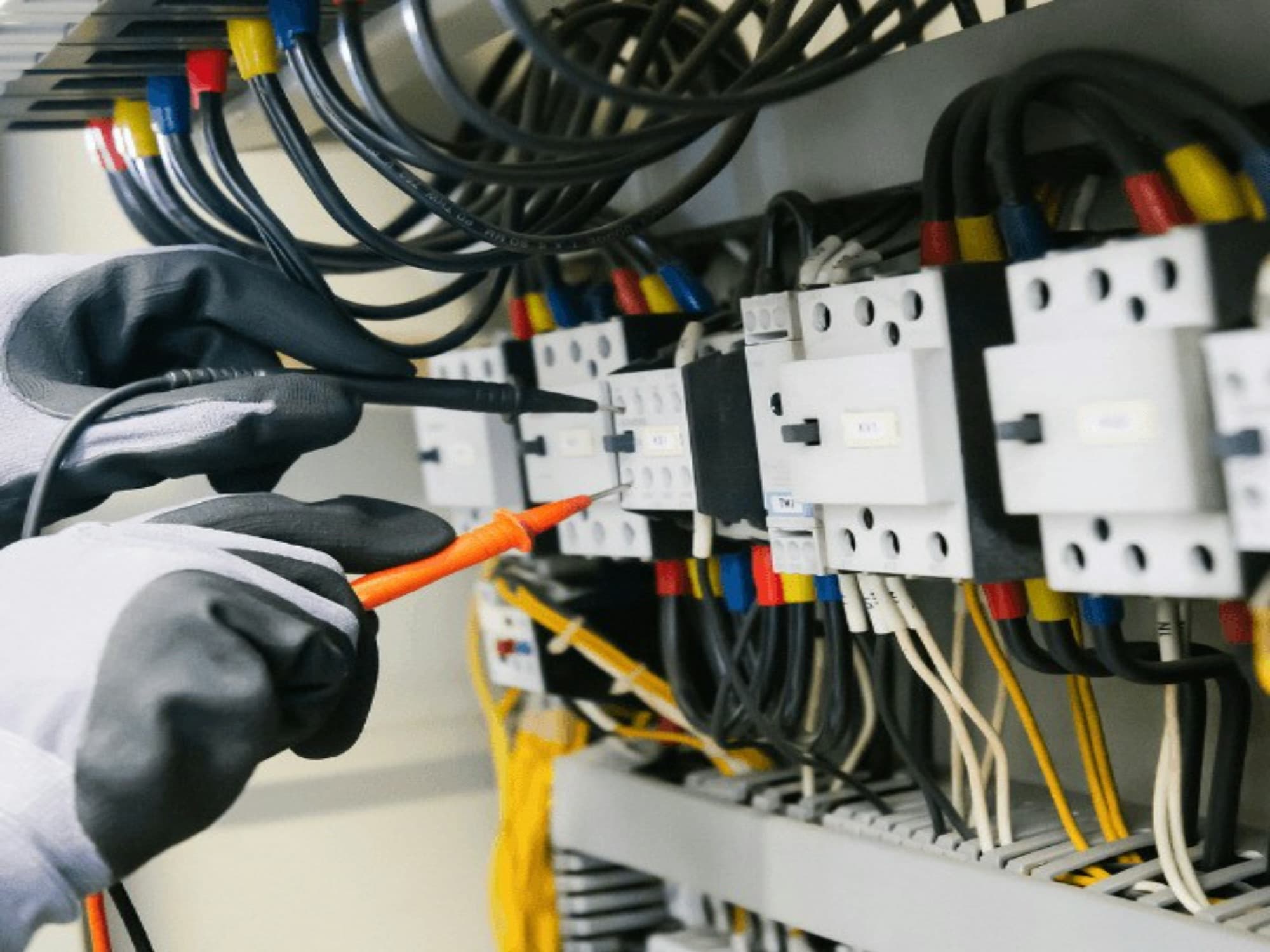 Licensed electrician testing wiring inside an electrical panel