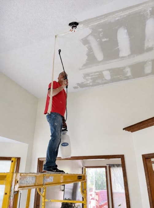 Ken repairing a tall living room ceiling